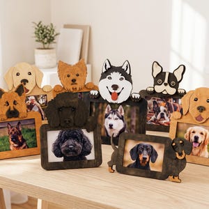 May include: A collection of six wooden picture frames, each featuring a carved, painted dog head and paws at the top. The frames display various dog breeds, including a German Shepherd, Golden Retriever, Poodle, Husky, French Bulldog, and Dachshund.