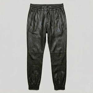 May include: Dark olive green leather joggers with a drawstring waist and zippered pockets. The pants have ribbed cuffs at the ankles and a relaxed fit. These leather joggers are a stylish addition to any wardrobe.