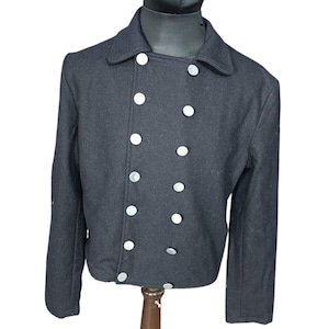 May include: A dark navy blue double-breasted jacket featuring a wide collar and two vertical rows of silver-toned circular buttons. The jacket has long sleeves and a structured fit, displayed on a mannequin torso to show the front design.