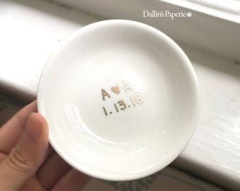 Puede incluir: Plato de anillo de cerámica blanca con letras doradas que dicen "A ♥ A 1.13.18".