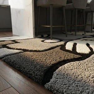 May include: A textured area rug with a unique pattern in shades of brown, beige, and white. The rug has a soft, plush appearance and is placed on a wooden floor. The design features organic shapes and dark brown outlines.