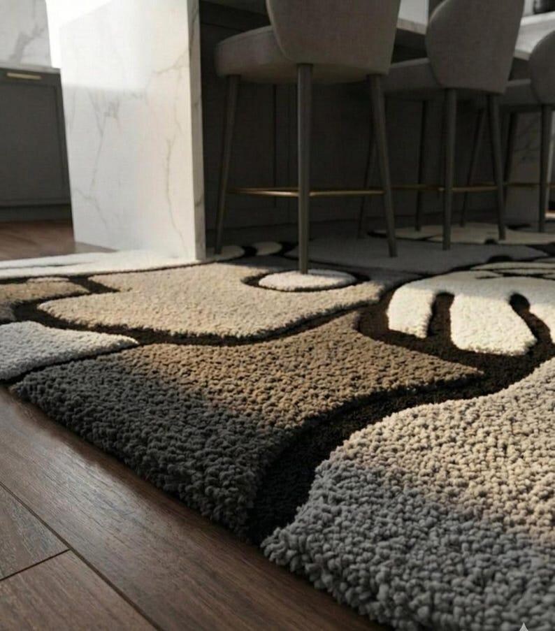 May include: A textured area rug with a unique pattern in shades of brown, beige, and white. The rug has a soft, plush appearance and is placed on a wooden floor. The design features organic shapes and dark brown outlines.