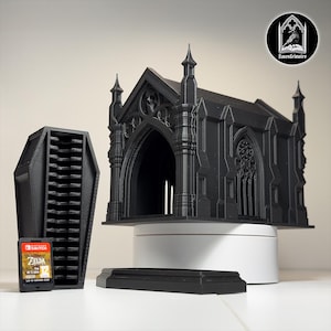 May include: A black gothic-style Switch game cartridge holder and a matching chapel-shaped game case. The chapel has intricate architectural details. A coffin-shaped cartridge holder and a game cartridge are also visible.