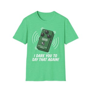 Puede incluir: Camiseta verde con una ilustración de dibujos animados de un pedal de guitarra MXR Carbon Copy Delay verde y ondas de sonido blancas. El texto "I DARE YOU TO SAY THAT AGAIN!" está impreso debajo.
