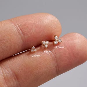 May include: Three gold stud earrings, each featuring a cluster of three small clear stones arranged in a triangular shape. The earrings are labeled with sizes 2.5mm, 3.5mm, and 4.5mm, indicating their respective widths in millimeters.