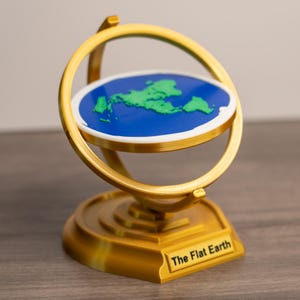 以下が含まれることがあります： 金色の装飾的な平面地球モデル。モデルは、緑の大陸を持つ青い円盤を特徴とし、金色のリングとベースで囲まれています。ベースには「The Flat Earth」というテキストがあります。
