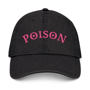 Peut inclure: Casquette de baseball noire avec le mot "POISON" brodé en rose, avec des motifs d'étoiles dans les lettres. La casquette a une visière incurvée et un bouton sur le dessus.
