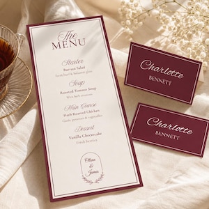 May include: A tall rectangular menu card with a cream background and deep red border, listing courses including Burrata Salad, Roasted Tomato Soup, Herb Roasted Chicken, and Vanilla Cheesecake, alongside two matching deep red place cards for Charlotte Bennett.