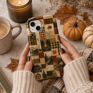 Puede incluir: Una funda para smartphone con un diseño de patchwork que muestra varias ilustraciones de temática al aire libre, incluyendo una fogata, montañas, pinos, una brújula y patrones de cuadros en tonos marrón, verde, naranja y crema.