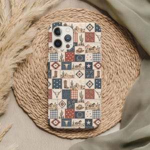 May include: A phone case with a patchwork design featuring cowboy-themed elements. The case has a mix of red, blue, and cream-colored squares with images of horses, cacti, cowboy boots, and steer skulls. The case is on a woven mat.
