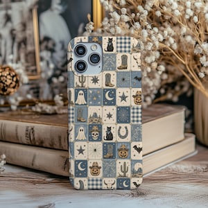 May include: A phone case featuring a grid pattern of blue and cream squares. Each square displays illustrations of western and spooky motifs including cowboy boots, cacti, ghosts, pumpkins, skulls, cats, bats, stars, moons, and spiderwebs.