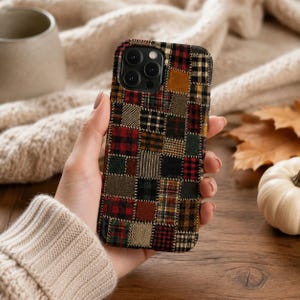 Puede incluir: Una funda para smartphone con un diseño de patchwork compuesto por varios cuadrados de aspecto textil en tonos rojos, verdes, marrones y negros. El patrón incluye cuadros, espiga y texturas lisas con costuras visibles entre cada cuadrado.