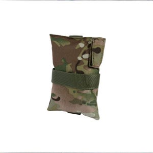 May include: A camouflage-patterned pouch with a green strap. The pouch is rectangular with a flap closure and a loop for attachment. The camouflage design features shades of green, brown, and tan.