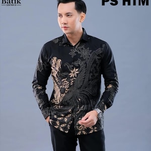 Puede incluir: Una camisa de manga larga con botones en color negro que presenta un estampado batik de flores y aves en tonos beige y gris oscuro. La camisa tiene un cuello estándar, una tapeta de botones frontal y puños. El texto "MOTIF PS HTM" aparece en la esquina superior derecha.