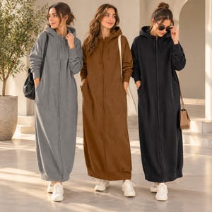 Puede incluir: Tres vestidos largos con capucha, de manga larga, con cremalleras frontales completas y bolsillos laterales. Los vestidos se presentan en colores lisos gris, marrón y negro, cada uno con capucha con cordones y puños acanalados en las mangas.