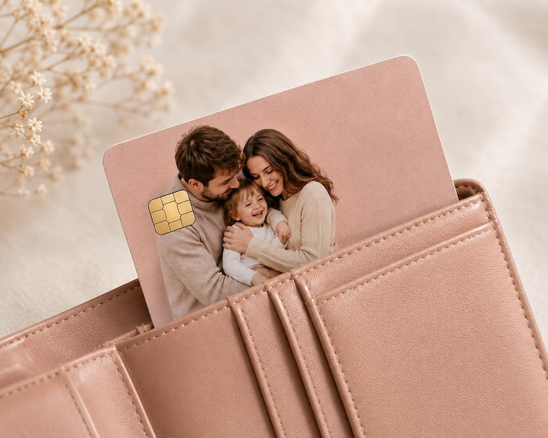 May include: A pink credit card with a family photo is partially inserted into a matching pink leather wallet. The card features a gold chip and a picture of a smiling family. The wallet has multiple card slots and a stitched design.