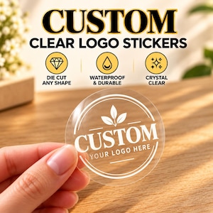 May include: A round, transparent sticker featuring a white circular border, a central leaf icon, and the text "CUSTOM YOUR LOGO HERE". The sticker is held up, showcasing its clear material. Text above highlights features: "DIE CUT ANY SHAPE", "WATERPROOF & DURABLE", and "CRYSTAL CLEAR".