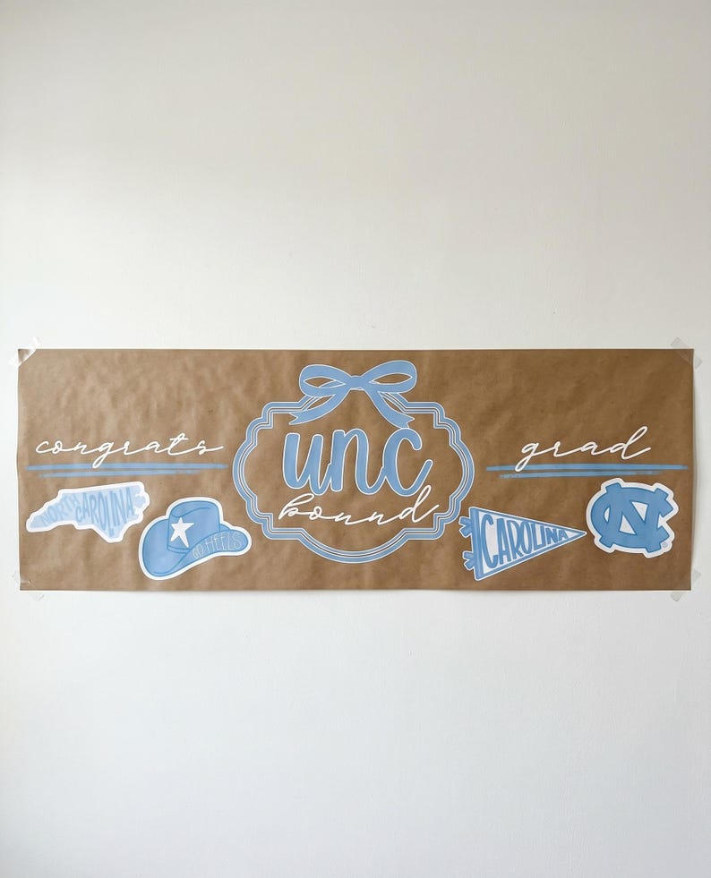 May include: A brown banner with light blue text and graphics. The banner says "congrats grad" with "unc board" in the center. There are also several light blue graphics of a hat, a pennant, and the state of North Carolina.