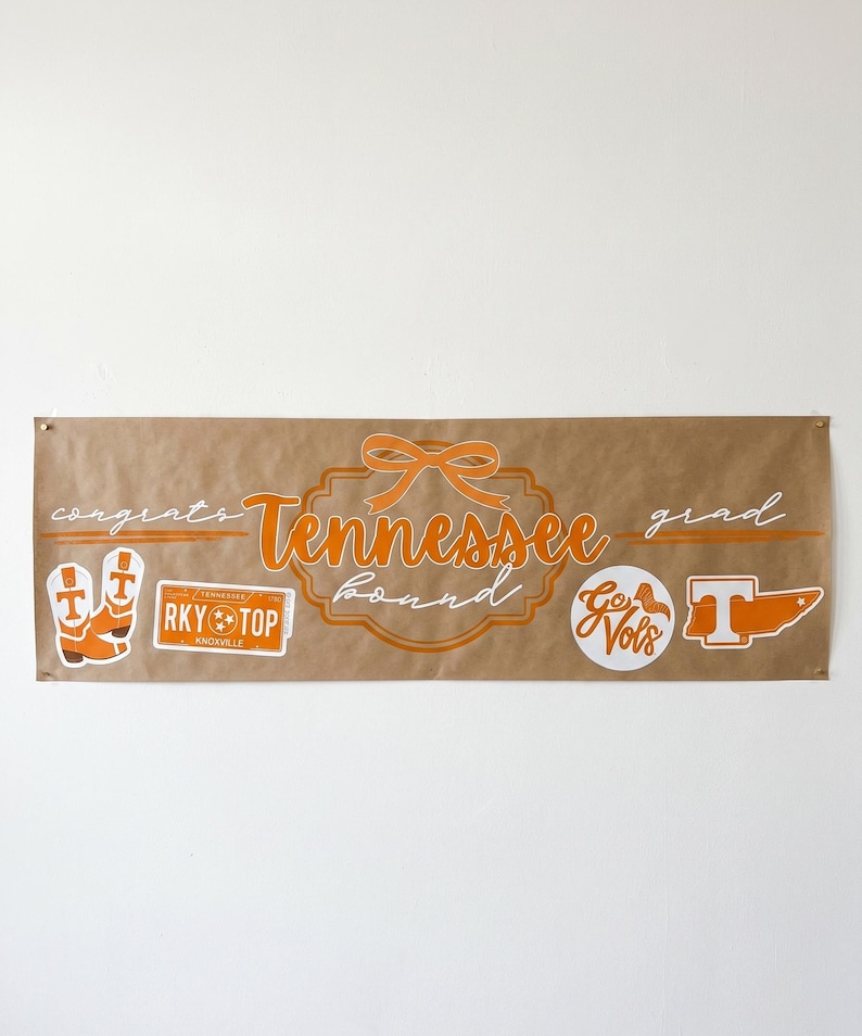 May include: A brown banner with orange text and graphics. The banner says "congrats Tennessee bound grad" with a bow graphic. Additional graphics include cowboy boots, a "RKY TOP Knoxville" sticker, a "Go Vols" circle, and a "T" graphic.