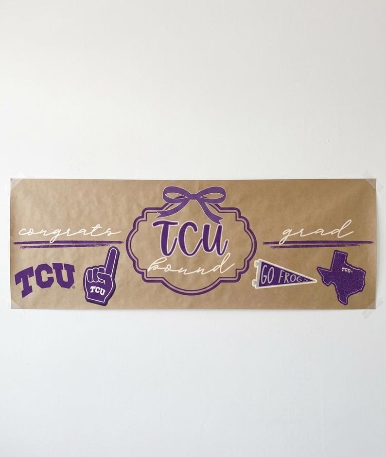 May include: A brown banner with purple text and graphics. The banner says "congrats grad" and features the letters "TCU" in a decorative font. Additional graphics include a foam finger, a pennant, and a Texas outline.