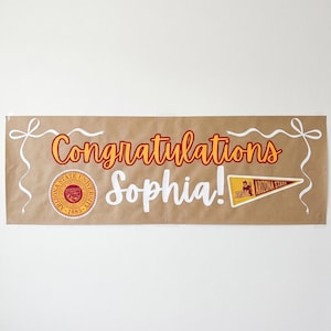May include: A brown banner with the words "Congratulations Sophia!" in red and white script. The banner includes Arizona State University logos and white ribbon accents, perfect for a graduation celebration.