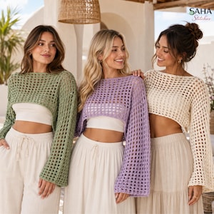 Könnte beinhalten: Drei langärmelige Häkelpullover in Salbeigrün, Lavendel und Creme. Jeder Pullover hat ein weites, offenes quadratisches Strickmuster, einen U-Boot-Ausschnitt und eine kurze Passform, getragen über schlichten weißen Oberteilen und hellen Hosen.