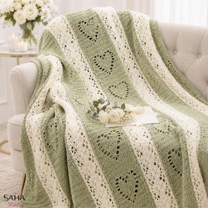 Peut inclure: Une couverture au crochet présentant des bandes verticales alternées de couleur vert sauge et blanc crème. Les sections vert sauge affichent un motif de cœur répétitif en mailles ajourées, tandis que les sections crème présentent un motif en dentelle.