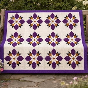 Könnte beinhalten: Ein Steppdecke mit einem sich wiederholenden Sternmuster in Violett-, Hellbraun- und Schwarztönen auf cremefarbenem Grund. Das Design besteht aus zwölf quadratischen Blöcken in einem Raster, umrahmt von einem violetten Rand mit Gitterstruktur.