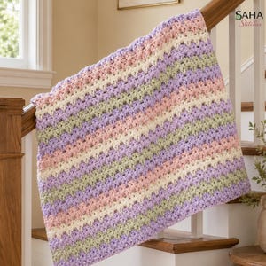May include: A crocheted blanket featuring a repeating striped pattern in soft pastel shades of lavender, cream, light pink, and sage green. The textile has a textured, open-stitch design and includes the text SAHA Stitches in the upper right corner.