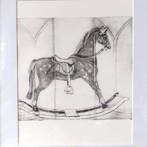 May include: A framed black and white print of a rocking horse. The horse is depicted with a saddle and bridle, mounted on a curved base. The background features an arched design, adding a vintage aesthetic.