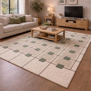 May include: A rectangular area rug featuring a cream-colored base with a grid pattern of thin brown lines. The design includes alternating light beige squares and smaller, solid sage green square accents placed at the intersections.