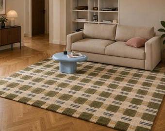 May include: A beige and green patterned area rug with a geometric design. The rug features a repeating pattern of green squares with yellow and blue accents. A light blue coffee table and a beige sofa are in the background.