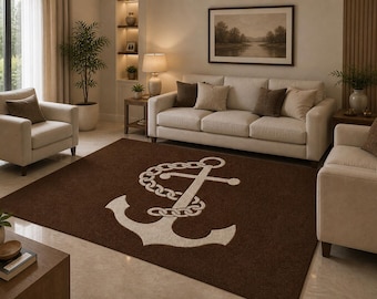 May include: A brown rectangular area rug with a large white anchor design. The anchor is connected to a chain. The rug is placed in a living room with a sofa, chairs, and a framed picture on the wall.