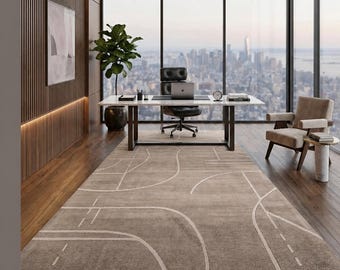 May include: A modern office space with a large window overlooking a cityscape. The room features a white desk, black leather chair, and a patterned rug in shades of beige and white. A potted plant and a side chair complete the decor.
