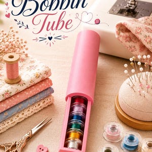 Puede incluir: Un contenedor de almacenamiento cilíndrico rosa con la etiqueta Bobbin Tube, que contiene una pila vertical de bobinas de máquina de coser de colores. El contenedor está rodeado de suministros de costura, telas, un alfiletero y tijeras.