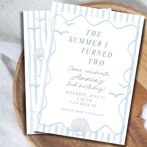 Può includere: Un biglietto d'invito di compleanno rettangolare con strisce verticali azzurre, illustrazioni di conchiglie e gabbiani e un bordo ondulato. Il testo recita: THE SUMMER I TURNED TWO, Come celebrate Annie's 2nd birthday!, SATURDAY, JUNE 27, 3:00 PM, 1234 MAIN ST., RSVP TO MOM 555-123-4567.