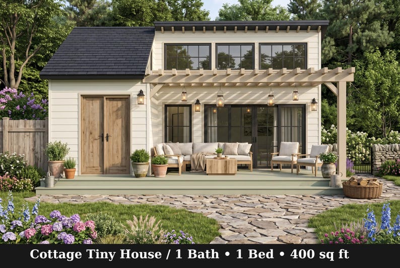 Peut inclure: Une petite maison de type cottage avec un bardage blanc, un toit sombre et une porte en bois. L'ext&eacute;rieur comprend une terrasse avec un canap&eacute; d'angle, deux chaises et une pergola avec des lumi&egrave;res suspendues. Texte : Cottage Tiny House / 1 Bath / 1 Bed / 400 sq ft.