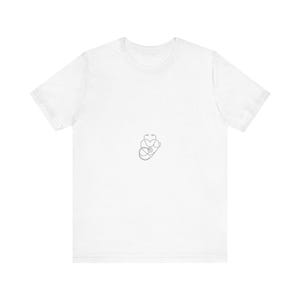 Könnte beinhalten: Ein weißes T-Shirt mit kurzen Ärmeln und einer kleinen, zentrierten schwarzen Strichzeichnung. Das Motiv zeigt ein Stethoskop in Form eines Herzumrisses, wobei das Bruststück und die Ohrbügel in einem durchgehenden Linienstil erkennbar sind.