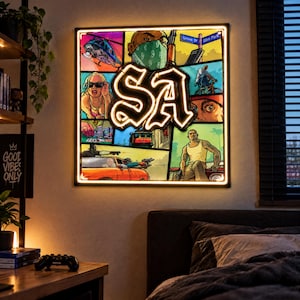 Peut inclure: Une décoration murale LED carrée présentant un collage d'illustrations de style bande dessinée tirées d'un jeu vidéo, centrée sur les lettres SA illuminées dans une police gothique, entourée d'un cadre lumineux sur un mur.