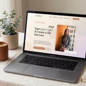 May include: A laptop displaying a website with the text "Find Your Inner Light & Create a Life You Love." Beside it are a terracotta mug with coffee, a potted plant, and a closed notebook. The laptop is on a white tablecloth.