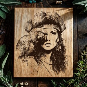 May include: A rectangular wooden plaque featuring a dark brown laser-engraved illustration of a person wearing a pirate hat with a parrot perched on their shoulder. The artwork displays intricate shading and fine lines on a light wood grain surface.