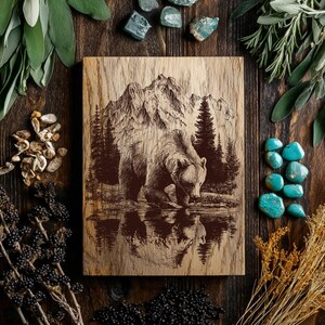 May include: A rectangular wooden plaque featuring a dark brown laser-engraved illustration of a grizzly bear standing near a reflective body of water, with a backdrop of dense pine trees and jagged mountain peaks under a clear sky.