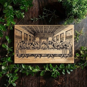 May include: A rectangular wooden plaque featuring a detailed engraving of Leonardo da Vinci's "The Last Supper." The artwork depicts the biblical scene with figures seated around a long table. The plaque is surrounded by green foliage.
