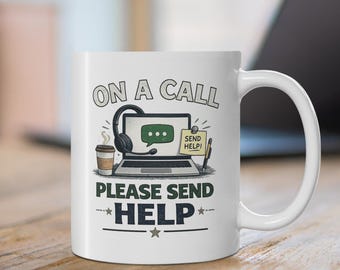 May include: A white ceramic mug featuring a graphic of a laptop with a headset, a coffee cup, and a sticky note that says SEND HELP. The text ON A CALL PLEASE SEND HELP is printed in dark grey and blue lettering above and below the illustration.