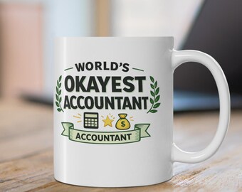 May include: A white ceramic mug featuring the black text "WORLD'S OKAYEST ACCOUNTANT" with green leaf accents, a black calculator icon, a yellow star, and a yellow money bag icon above a green banner with the word "ACCOUNTANT" printed in black.