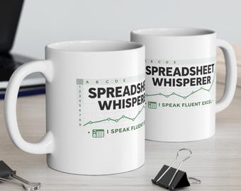 May include: Two white ceramic mugs featuring a graphic of a spreadsheet grid with the text SPREADSHEET WHISPERER and I SPEAK FLUENT EXCEL in black and green, accompanied by a small green line graph icon and a calculator icon on the side.