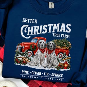 May include: A navy blue sweatshirt featuring a graphic of two English Setter dogs wearing red plaid bandanas in front of a red pickup truck. The text reads SETTER CHRISTMAS TREE FARM, PINE, CEDAR, FIR, SPRUCE, CUT & CARRY, and ESTD 1972.