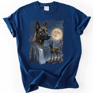May include: Navy blue t-shirt featuring a detailed illustration of two dogs with a waterfall, full moon, and forest background. The artwork showcases a dog's portrait and a full body image of a dog standing on a rock.