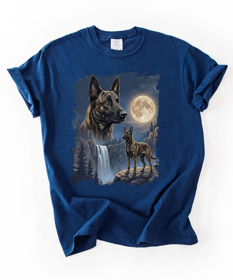 May include: Navy blue t-shirt featuring a detailed illustration of two dogs with a waterfall, full moon, and forest background. The artwork showcases a dog's portrait and a full body image of a dog standing on a rock.