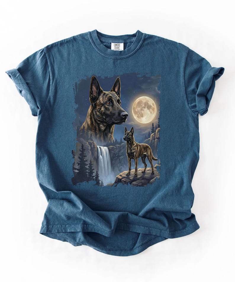 May include: A blue t-shirt featuring a detailed illustration of a dog with a waterfall, full moon, and forest scene. The dog is depicted in two sizes, with a close-up of the head and a full body shot. The design is centered on the shirt.